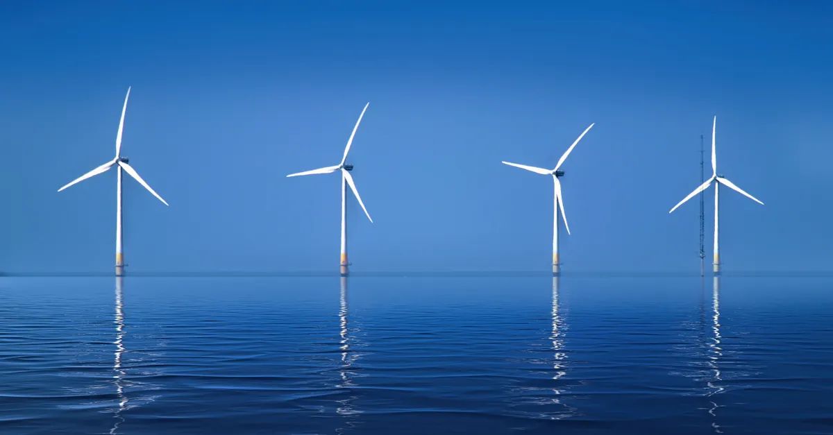 Offshore wind turbines reflected in calm blue water