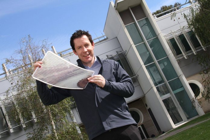 Close-up of a flexible organic photovoltaic film held up to light, showing its thin printable structure