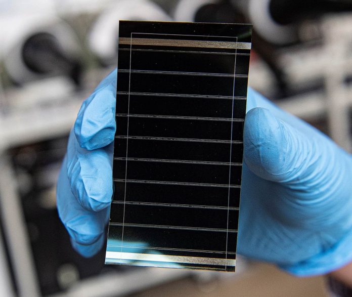 Perovskite solar cell held in a gloved hand in a research laboratory for the perovskite durability article