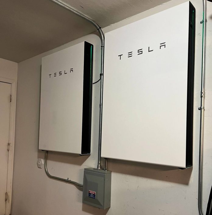 Home Battery Cost 2026: Tesla Powerwall vs Competitors Two Tesla Powerwall 3 battery units installed inside a residential home for the home battery cost comparison article