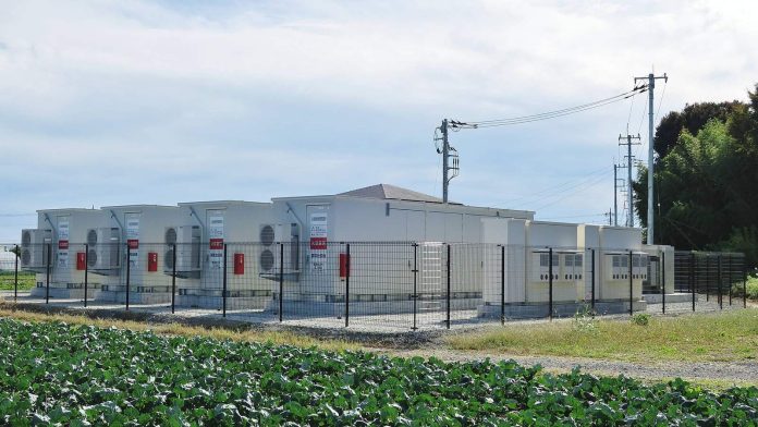 Grid-scale battery energy storage station with rows of outdoor battery units at dusk