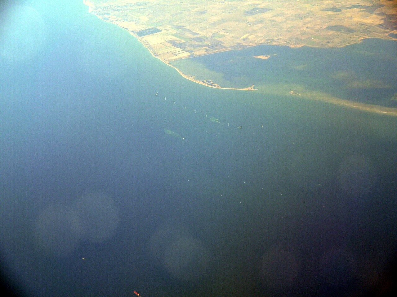 Aerial view of a row of offshore wind turbines along the coast